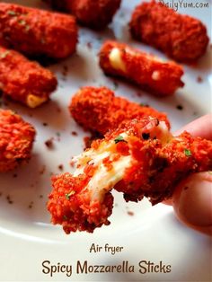 someone holding up some food on a plate with the words air fryer spicy mozzarella sticks