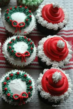 cupcakes decorated with red, green and white frosting are arranged on a table