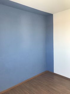 an empty room with blue walls and wood floors