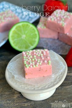 a piece of cake on a plate next to some strawberries and limes in the background