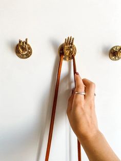 a hand is holding onto the handles of a pair of door knobs on a white wall