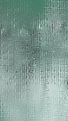 rain drops falling down on the surface of a window with green and white colors in the background