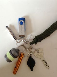 an assortment of keys and other personal items on a white surface with a blue keychain