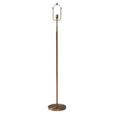 a tall metal and wood floor lamp with a candle on it's base, against a white background