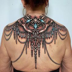 the back of a woman's neck is adorned with intricate designs and jewels on it