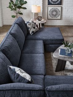 a living room with a blue couch and coffee table in front of a brick wall