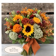 a bouquet of sunflowers and other flowers in a vase with an orange ribbon