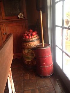 a bucket full of fruit sitting next to a window with a wooden pole in it