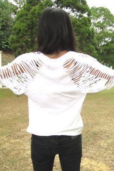 a woman standing in the grass with her back to the camera, wearing black jeans and a white t - shirt