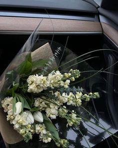 a bouquet of white flowers sitting on top of a car window sill next to a piece of paper