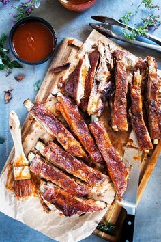 sliced up meat sitting on top of a cutting board next to a bowl of sauce