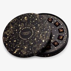 two black boxes with gold zodiac signs on them and stars in the sky around them