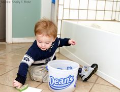 a little boy playing with his toys on the floor in front of a bath tub