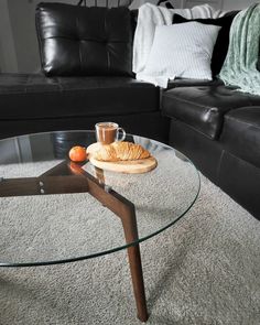 a glass table with some food on top of it in front of a black couch