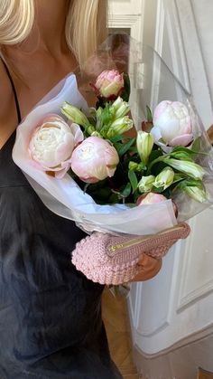 a woman in a black dress holding a bouquet of pink and white flowers on her left hand