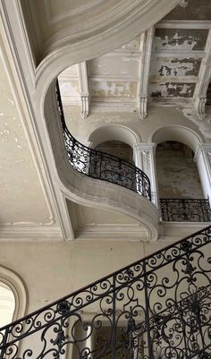 an ornate staircase with wrought iron handrails in a large building that looks like it has been painted white