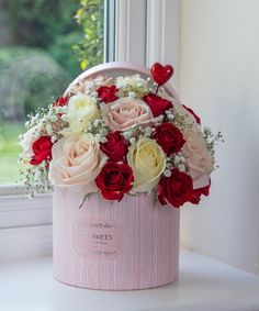 a pink bucket with roses and baby's breath in it sitting on a window sill