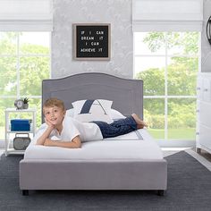 a young boy laying on top of a bed