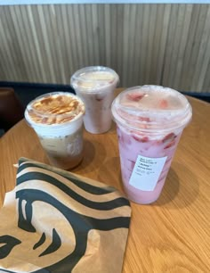 three drinks are sitting on a wooden table