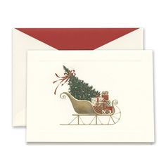 a christmas card with a sleigh and presents on it's back, in front of a red envelope