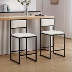 two white barstools sitting next to each other in front of a counter