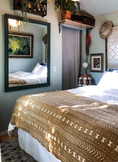 a large bed sitting under a mirror next to a wall mounted plant on top of it