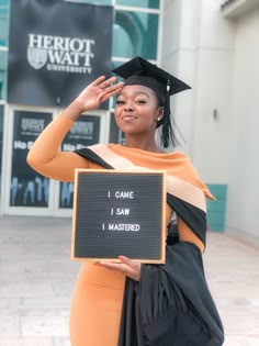 a woman in a graduation gown holding a sign