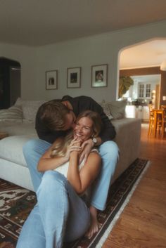 a man and woman sitting on top of a couch in a living room next to each other