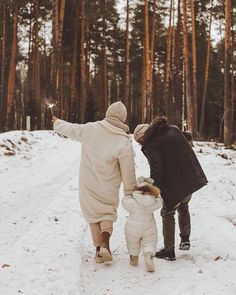 two adults and a child walking in the snow