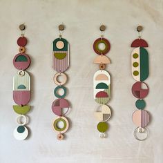 three wooden wall hangings with circles and rings on them, one is green, the other is pink