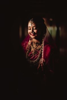 a woman in a red and gold sari looks at the camera while wearing a veil