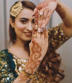 a woman with henna holding her hands up to show the ring on her finger