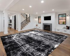 a large black and white rug in the middle of a living room with stairs on either side