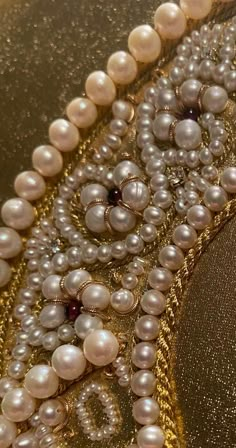 a close up of pearls and other beads on a table cloth with gold trimming