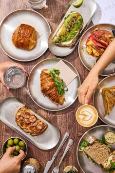 people are sitting at a table with many different plates and dishes on it, including croissants