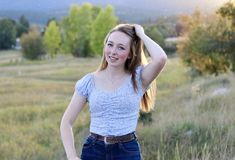 a young woman standing in a field with her hands on her head