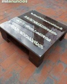 a coffee table made out of glass and wood with writing on the top, sitting on a brick floor