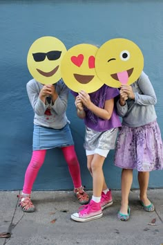 two girls are holding up smiley face masks