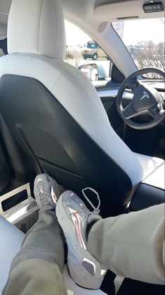 someone is sitting in the driver's seat of a car with their feet on the steering wheel