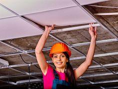 a woman in an orange hard hat is hanging from the ceiling with her arms above her head