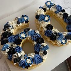 two cakes decorated with blue and white icing are sitting on a counter top next to each other