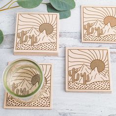 three coasters with desert scenes on them next to a cup and some green leaves