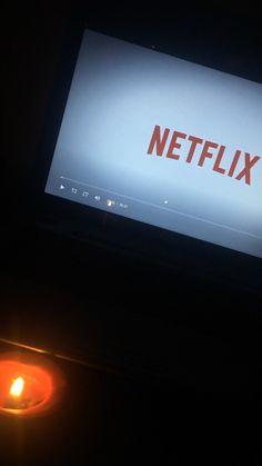 a television screen with the netflix logo lit up in front of it and a candle next to it