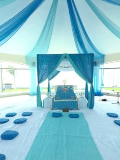 a bed with blue sheets and pillows in a room that looks like it has been set up for a wedding