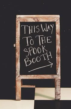 this way to the spook booth is written on a blackboard in front of a checkered floor