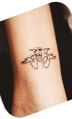 a tattoo on the leg of a person with a small cat in it's arm