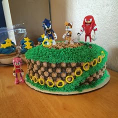 a birthday cake decorated with sonic the hedgehog figures and other figurines on a table