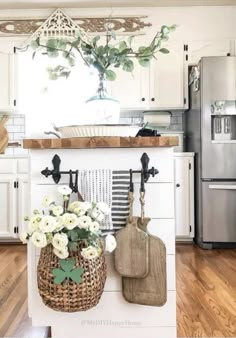 a kitchen with white cabinets and flowers in a basket on the island, along with utensils