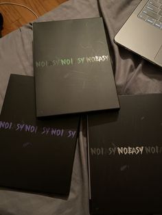 four notebooks with writing on them sitting next to a laptop