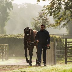 a man leading a horse down a dirt road